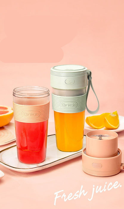 Juice blender with a glass of juice on a pink background