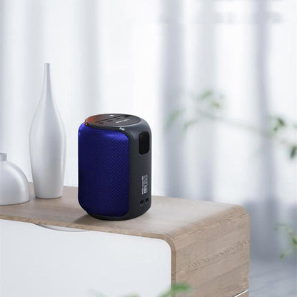 Blue and black portable speaker on a wooden surface with white vases and curtains in the background