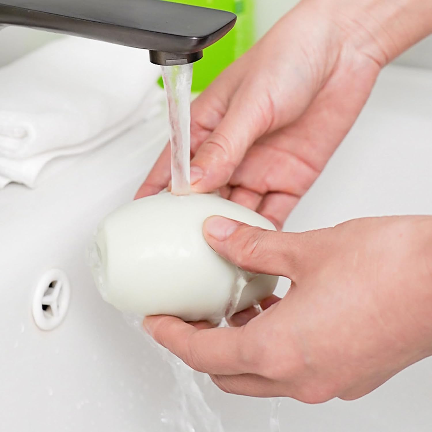 Person washing an lint roller under running water in a sink.