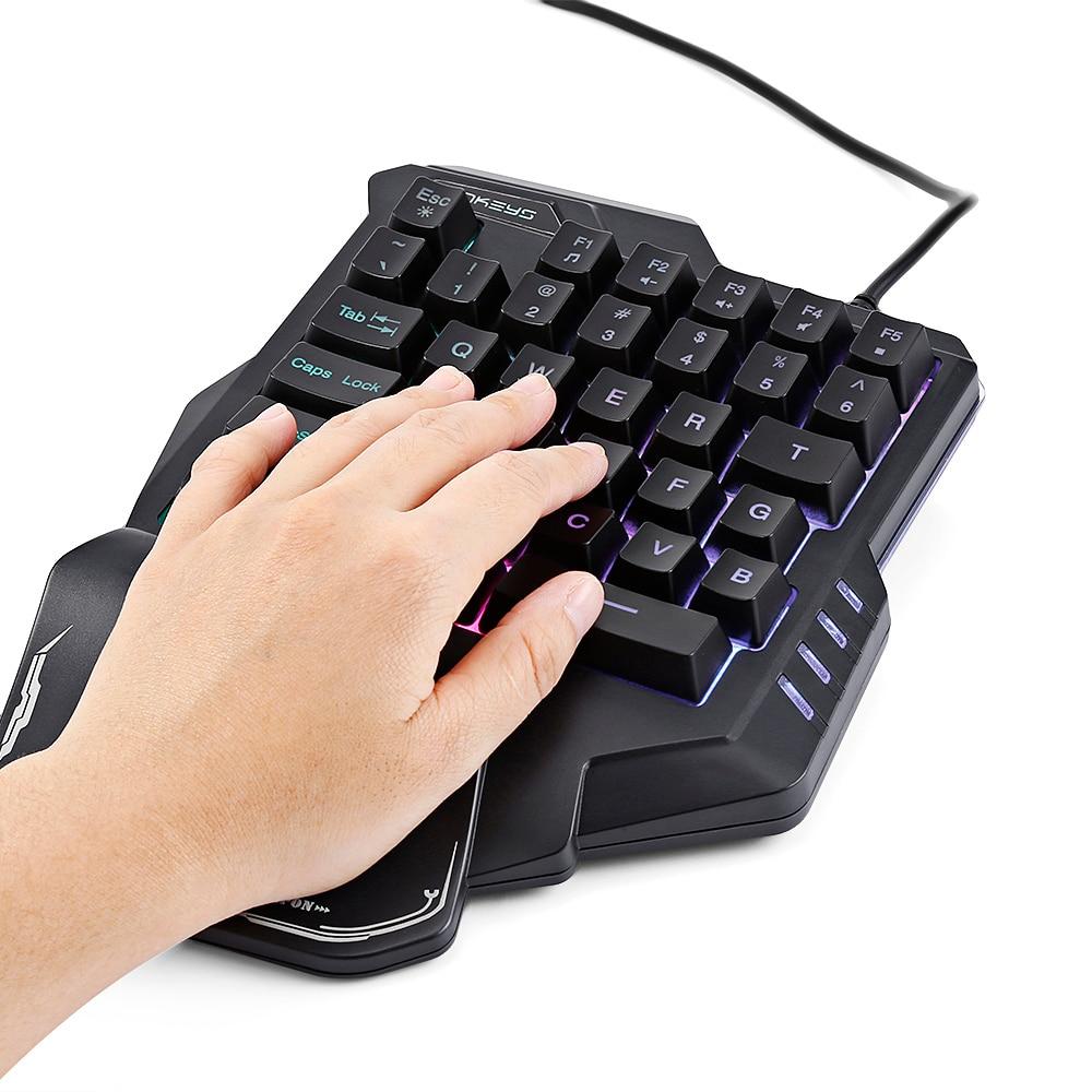 Hand using a black ergonomic keyboard with RGB lighting on a white background