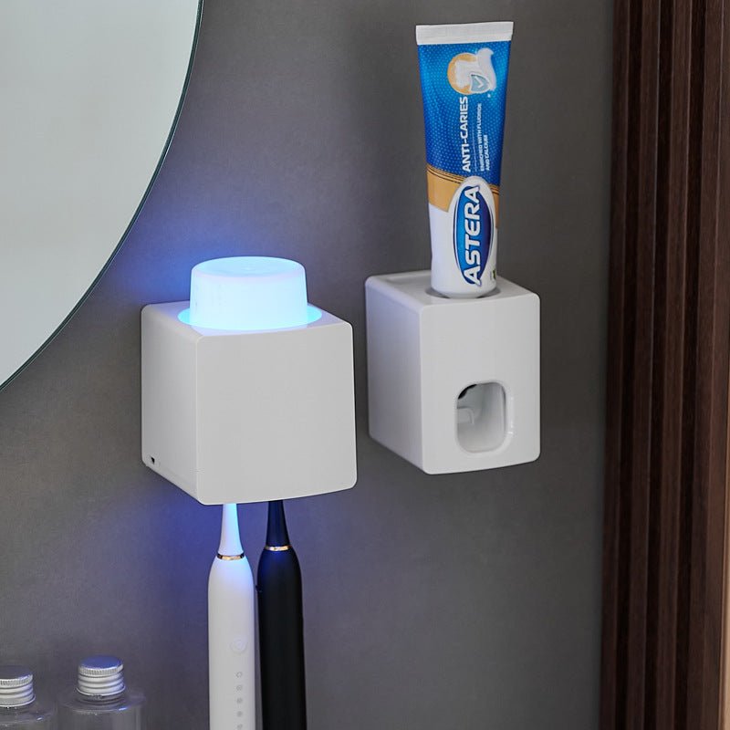 Two white square holders on a gray wall with a toothbrush and tube of toothpaste.