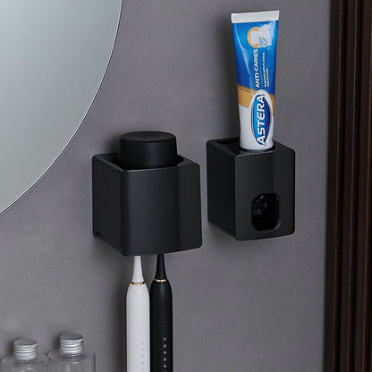Black wall-mounted toothbrush holder with a toothpaste tube on a gray bathroom wall.