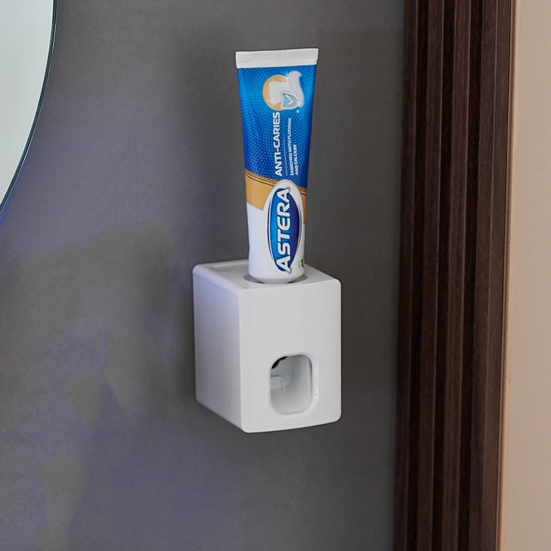 Asteria toothpaste tube on a white holder against a gray wall.
