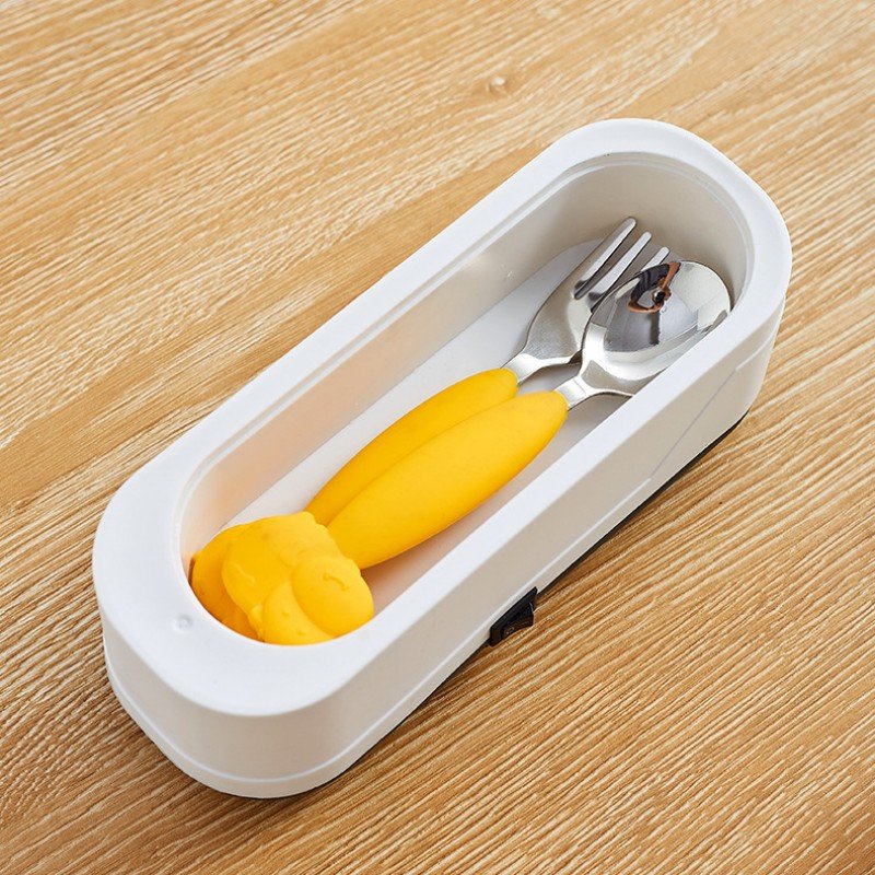 Set of yellow utensils in a white case on a wooden surface