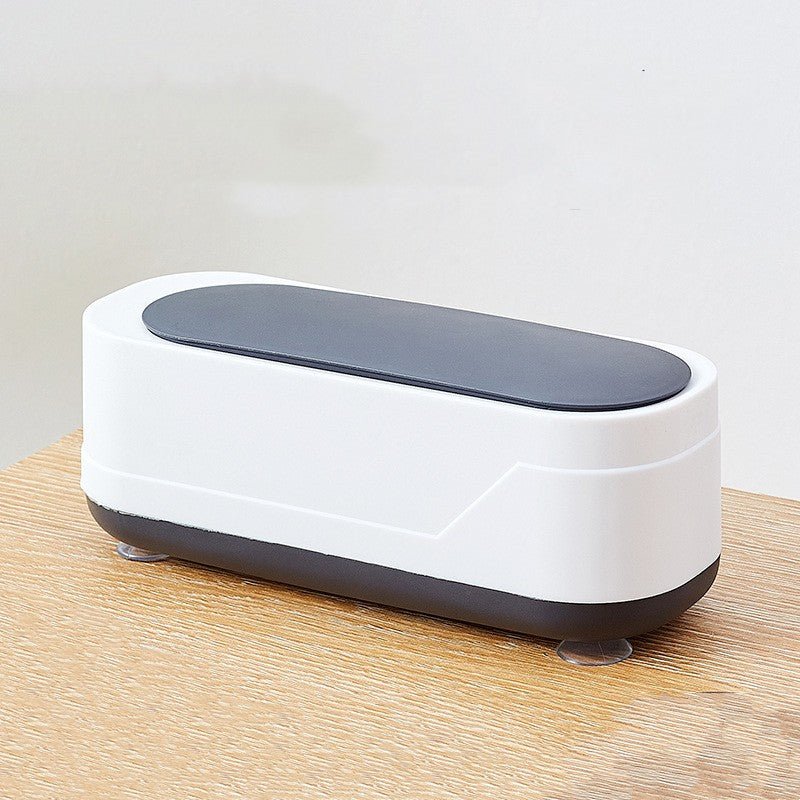 White and gray electronic device on a wooden surface with a light gray background