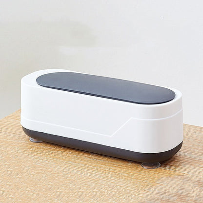 White and gray electronic device on a wooden surface with a light gray background