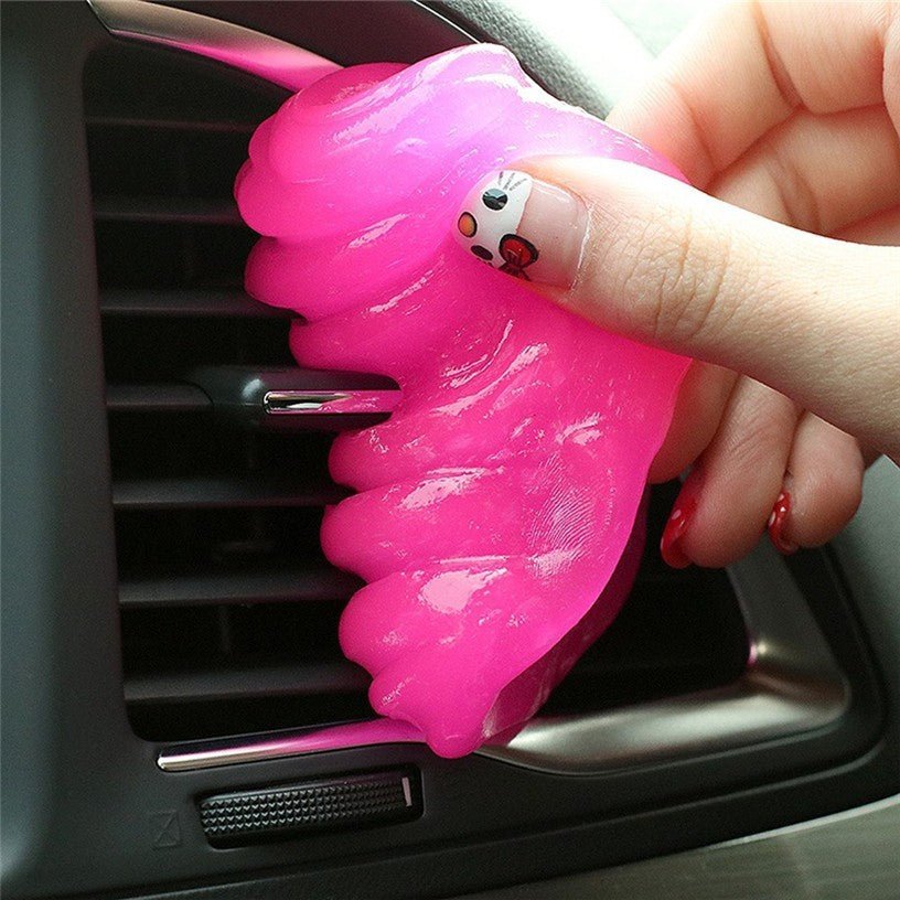 Pink car air freshener shaped like a jellyfish being held over a car's air vent.