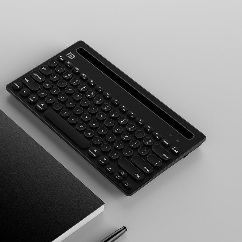 Black keyboard on a light gray surface with a black notebook and pen.